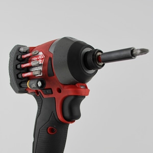 May include: A red and black cordless drill with a black handle and a red battery pack. The battery pack has the text "M18 REDLITHIUM XC5.0" and "Milwaukee REDLITHIUM" on it.