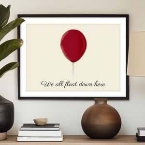 May include: A framed print with a red balloon and the text "We all float down here".
