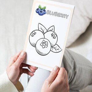 Puede incluir: Una p&aacute;gina para colorear en blanco y negro con un ar&aacute;ndano y la palabra "Blueberry" impresa arriba.