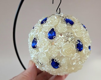 Esfera con pedrería y cuentas. Aproximadamente 10 cm (4 pulgadas), dependiendo del tamaño de las cuentas. Color azul y marfil.