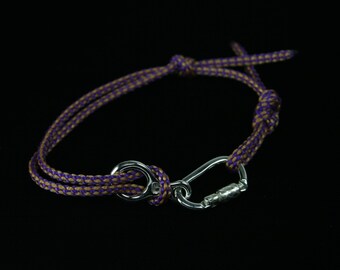 May include: A purple and brown braided rope bracelet with a silver carabiner clasp.
