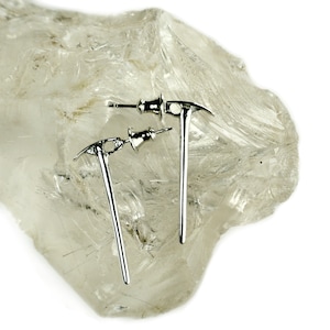 May include: A pair of silver pickaxe earrings. The earrings are small and delicate, and they are perfect for adding a touch of whimsy to any outfit.