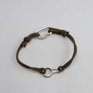 May include: A green paracord bracelet with a silver carabiner and a silver ring clasp.