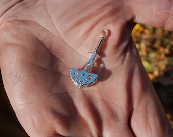 Op de afbeelding: Een zilveren ijs-klimgereedschap met een veermechanisme en een kleine, puntige punt. Het gereedschap is ontworpen voor gebruik bij ijs-klimmen en bergbeklimmen.