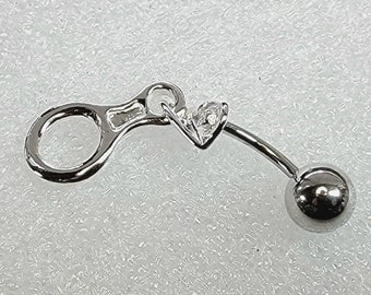 May include: Silver belly button ring with a small ball on the end and a decorative charm with a small clear stone.
