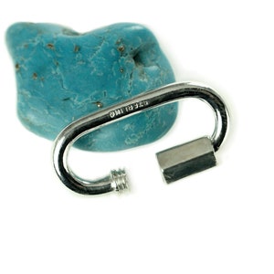 May include: A silver metal clasp with a rounded shape and a hexagonal end piece. The clasp is marked "STERLING".