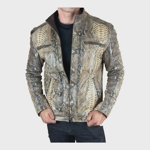 Pode incluir: Uma caneca de cerâmica branca com uma alça preta e o texto "But First, Coffee" em negrito preto. A caneca está sobre um fundo desfocado, sugerindo um ambiente acolhedor.