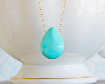 May include: A turquoise teardrop pendant necklace with a gold chain.