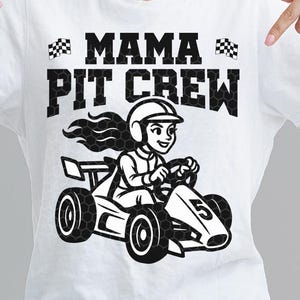 May include: White t-shirt featuring the text "MAMA PIT CREW" in black, with a cartoon illustration of a person driving a go-kart. The go-kart has the number 5 on it. The bottom of the shirt has the text "AI SVG PNG EPS DXF".
