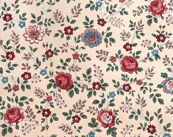 May include: A wallpaper pattern featuring a light peach background with a repeating floral design. The print includes dark red roses, smaller blue flowers, and green leaves connected by thin, winding white stems and delicate brown branches.