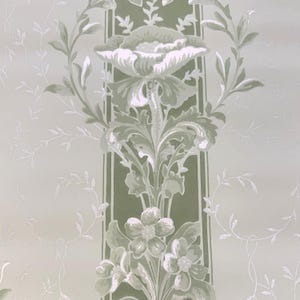 May include: Wallpaper featuring a vertical band of dark olive green with a repeating floral motif in light sage green and white. The pattern includes large blossoms and leafy stems centered within the stripe, flanked by delicate white vine silhouettes.
