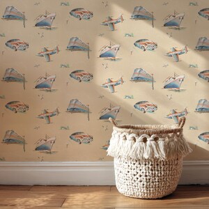 May include: A beige woven basket with a fringed trim sits on a wooden floor. The background is a wallpaper pattern featuring vintage cars, airplanes, and ships in shades of orange, blue, and beige.