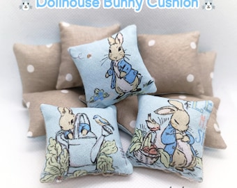 Könnte beinhalten: Puppenhaus-Hasenkissen, jeweils 4x4 cm groß. Die Kissen zeigen Illustrationen eines Hasen in einem blauen Jackett. Einige Kissen sind hellblau mit Hasenillustrationen, andere sind beige mit weißen Punkten. Der Text "Dollhouse Bunny Cushion" steht oben.