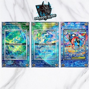 Könnte beinhalten: Drei Pokemon-Sammelkarten in transparenten Schutzhüllen. Die Karten zeigen blau-grüne Wasser-Illustrationen. Die Hüllen sind mit "Dragon Slabs" und einem Drachenlogo versehen. Die Karten sind Froakie, Frogadier und Mega Greninja.