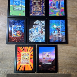 Puede incluir: Siete tarjetas enmarcadas con varias ilustraciones y dise&ntilde;os coloridos. Los marcos negros miden 12,7 x 17,8 cm. Las tarjetas presentan im&aacute;genes de criaturas y paisajes. El texto "5x7 Frame Examples" se muestra en un letrero de madera.