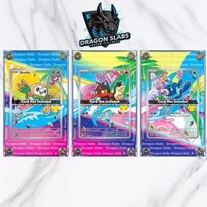 Op de afbeelding: Drie transparante displaycases voor ruilkaarten. Elke case bevat een andere Pokémon-kaart: Rowlet, Litten en Popplio. De kaarten staan tegen een kleurrijke achtergrond met de tekst "Dragon Slabs" en "Custom TCG Cases".