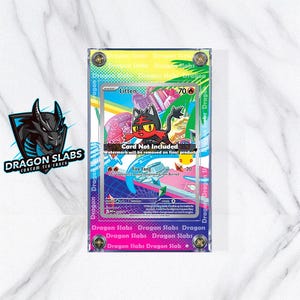 Op de afbeelding: Een heldere, rechthoekige koffer met een kleurrijke rand, met een Litten Pokémon-kaart. De kaart toont een cartoonkat met rode en zwarte vacht. De koffer heeft de tekst "Dragon Slabs" en "Card Not Included".