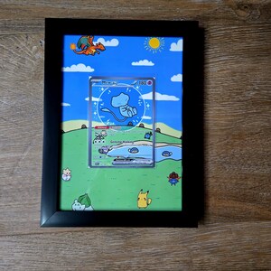 Puede incluir: Obra de arte enmarcada con una carta coleccionable de Pok&eacute;mon con un dise&ntilde;o Mew ex. La carta est&aacute; ambientada en un paisaje de dibujos animados con cielo azul, hierba verde y varios personajes Pok&eacute;mon. El marco es negro.