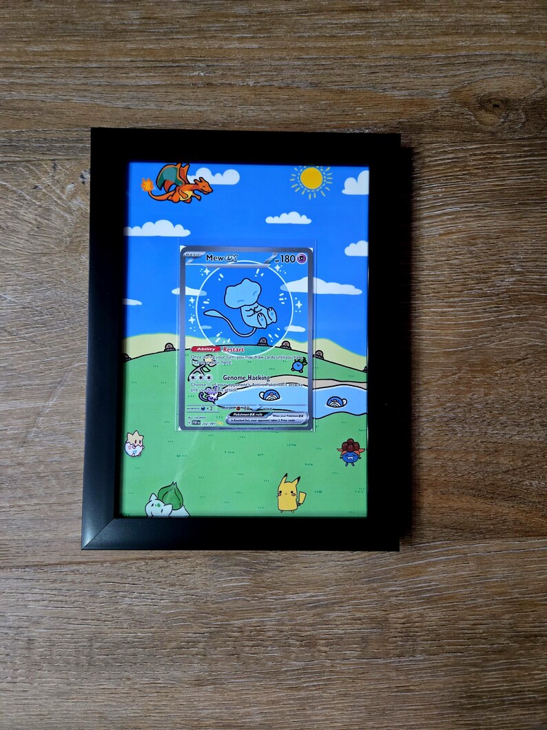 Puede incluir: Obra de arte enmarcada con una carta coleccionable de Pok&eacute;mon con un dise&ntilde;o Mew ex. La carta est&aacute; ambientada en un paisaje de dibujos animados con cielo azul, hierba verde y varios personajes Pok&eacute;mon. El marco es negro.