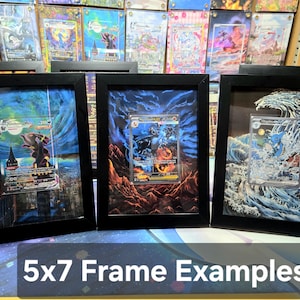 Puede incluir: Tres cartas coleccionables enmarcadas con marcos negros. Las cartas presentan arte y personajes de fantas&iacute;a coloridos. El texto "5x7 Frame Examples" est&aacute; en la parte inferior. El fondo incluye m&aacute;s cartas enmarcadas.