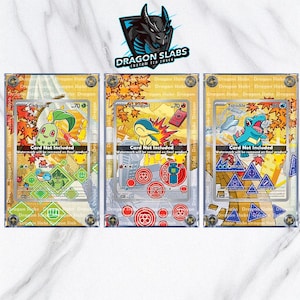 May include: Three rectangular clear acrylic trading card display cases featuring the Dragon Slabs logo at the top. Each case holds a colorful illustrated card depicting Chikorita, Cyndaquil, or Totodile, with text stating Card Not Included.