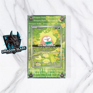 May include: A clear, protective case for a Pokémon trading card. The card features a Rowlet illustration with the text "Rowlet" and "Card Not Included". The case is labeled "Dragon Slabs" and has a green border.