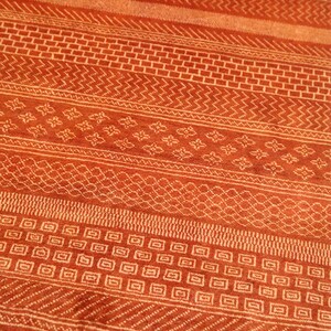 K&ouml;nnte beinhalten: Nahaufnahme eines roten und wei&szlig;en Teppichs mit geometrischen Mustern. Der Teppich hat eine Vielzahl von Mustern, darunter Quadrate, Rauten und Zickzacklinien.