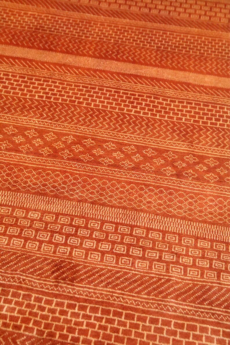 K&ouml;nnte beinhalten: Nahaufnahme eines roten und wei&szlig;en Teppichs mit geometrischen Mustern. Der Teppich hat eine Vielzahl von Mustern, darunter Quadrate, Rauten und Zickzacklinien.