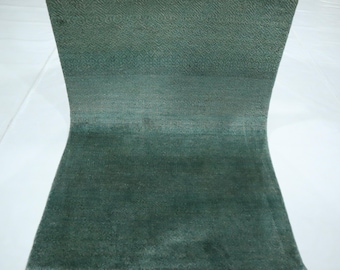 Op de afbeelding: Een teal-kleurig tapijt met een gradiënteffect, dat overgaat van een donkerdere tint aan de onderkant naar een lichtere tint aan de bovenkant. Het tapijt heeft een getextureerd oppervlak en wordt gepresenteerd tegen een witte achtergrond.