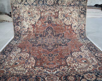 May include: A large, rectangular rug with an intricate, traditional design. The rug features a central medallion and corner designs in shades of red, navy blue, and cream. The rug is displayed on a concrete floor.