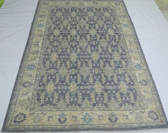 Puede incluir: Una alfombra azul y beige con un diseño floral detallado. La alfombra tiene un borde con flecos.