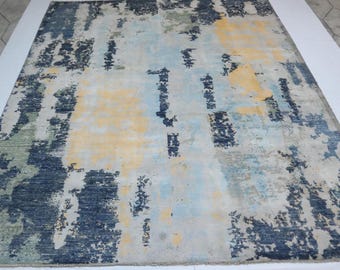 May include: Abstract area rug with a blue, yellow, and white color scheme. The rug has a distressed, faded look with a modern design.