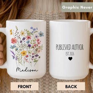 Könnte beinhalten: Zwei weiße Keramiktassen. Die linke Tasse zeigt einen bunten Aquarell-Wiesenblumenstrauß über dem Namen Madison in schwarzer Schreibschrift. Die rechte Tasse zeigt den schwarzen Text PUBLISHED AUTHOR, EST. 2026 und ein kleines schwarzes Herz.