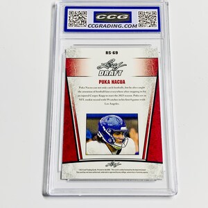May include: A Puka Nacua football trading card, graded and encased in a protective holder. The card features a photo of the player in a blue helmet and the text "DRAFT PUKA NACUA". The card has red and white accents.