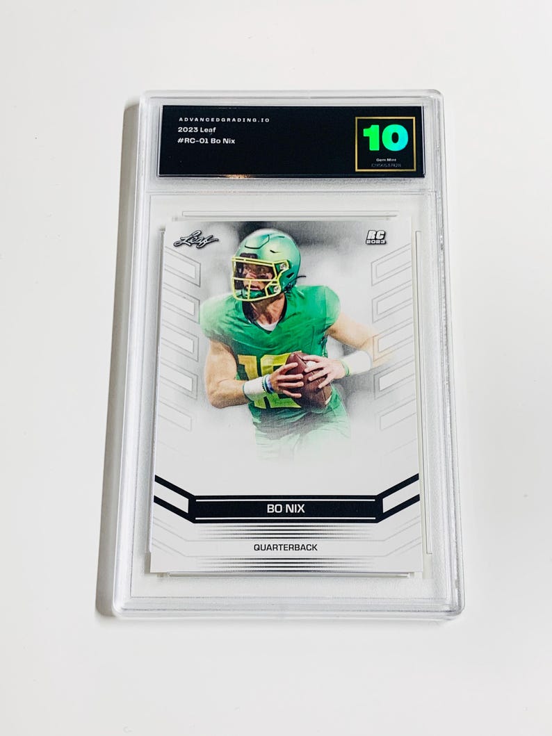 K&ouml;nnte beinhalten: Eine bewertete 2023 Leaf Bo Nix Footballkarte. Die Karte zeigt einen Spieler in gr&uuml;ner Uniform, der einen Football h&auml;lt. Die Karte ist in einem transparenten Kunststoffhalter eingeschlossen und mit 10 bewertet.