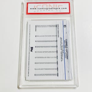 May include: A Carmelo Anthony trading card, graded and encased in a clear plastic holder. The card features player statistics and the Topps logo. The Iconic Grading Co. logo is visible at the top.