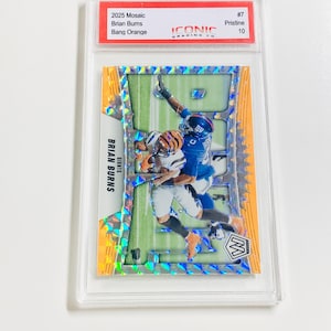 Puede incluir: Una tarjeta coleccionable de f&uacute;tbol con Brian Burns. La tarjeta tiene un dise&ntilde;o naranja y verde con el texto "2025 Mosaic Brian Burns Bang Orange". La tarjeta est&aacute; dentro de un protector transparente.