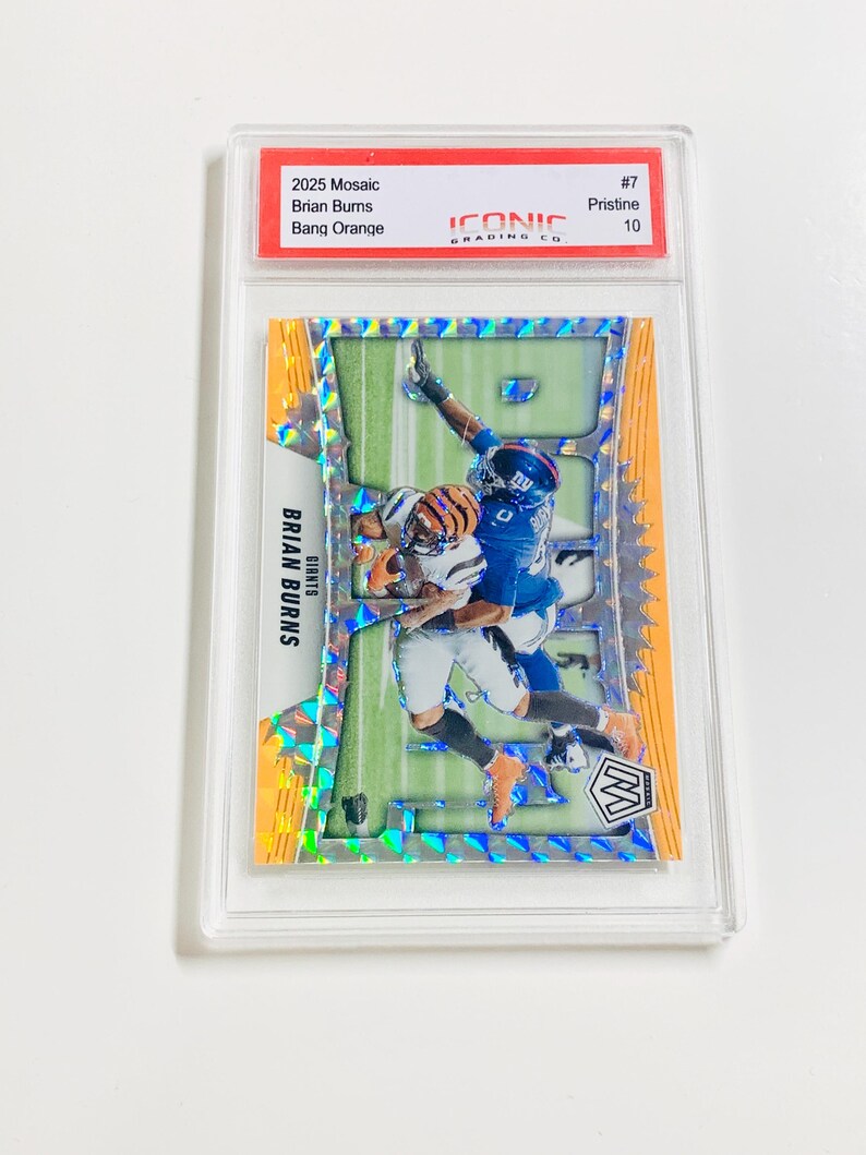 Puede incluir: Una tarjeta coleccionable de f&uacute;tbol con Brian Burns. La tarjeta tiene un dise&ntilde;o naranja y verde con el texto "2025 Mosaic Brian Burns Bang Orange". La tarjeta est&aacute; dentro de un protector transparente.