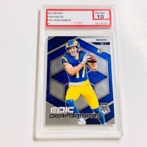 May include: A Puka Nacua football trading card from the 2025 Mosaic Epic Performers series. The card is graded Pristine 10 and features a player in a blue and yellow uniform. The card is encased in a protective holder.