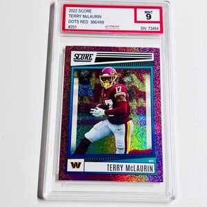 May include: A Terry McLaurin football trading card from the 2022 Score series, graded as Mint 9. The card features a player in a burgundy and gold uniform, with the Washington Commanders logo. The card is a Dots Red edition, numbered 366/499.