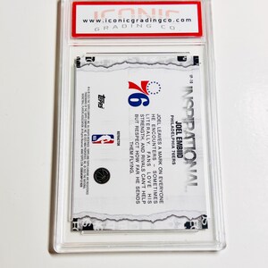 Puede incluir: Una tarjeta de baloncesto coleccionable dentro de un estuche de pl&aacute;stico transparente. La tarjeta presenta el logotipo de los 76ers de Filadelfia y texto sobre Joel Embiid. La parte superior del estuche tiene una etiqueta roja con el sitio web "www.iconicgradingco.com".