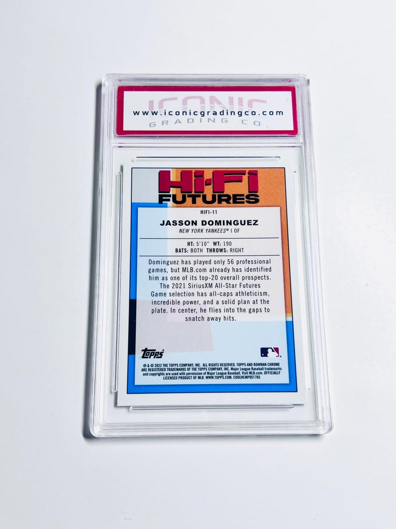 May include: A baseball card of Jasson Dominguez, a New York Yankees player, from the Hi-Fi Futures series. The card is encased in a clear plastic holder with a red and white label from Iconic Grading Co. The card's back features player stats and a description.