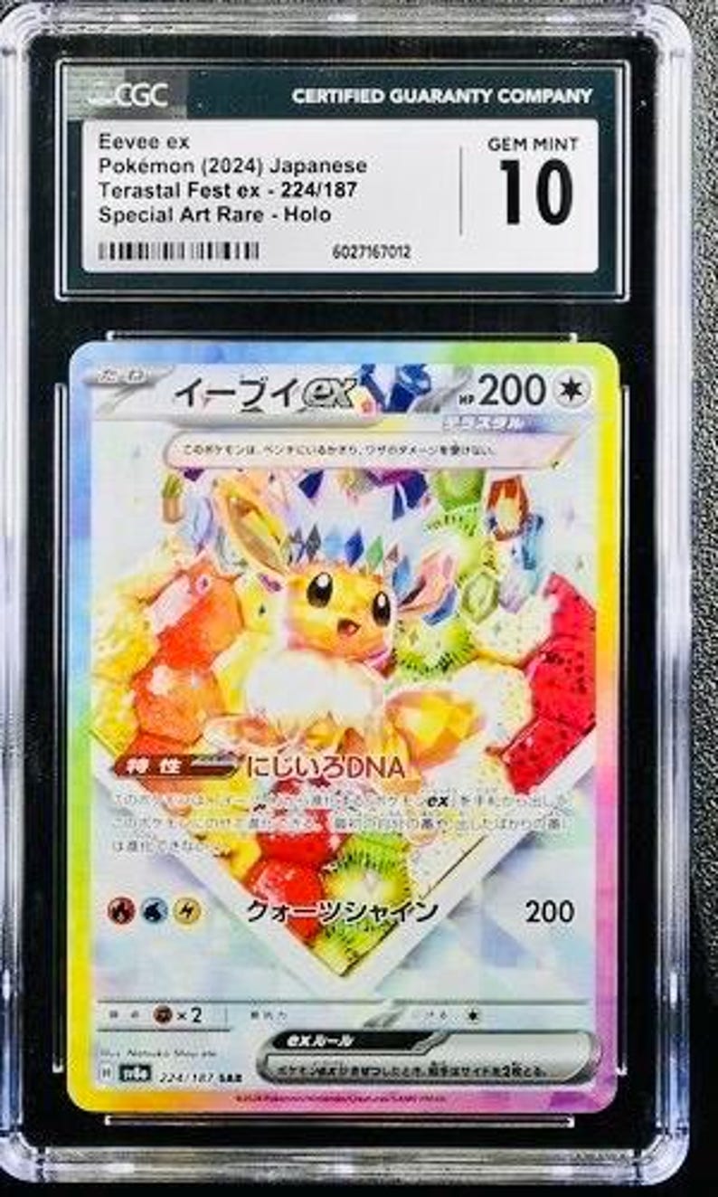Puede incluir: Una carta Pok&eacute;mon graduada con Eevee ex del set Terastal Fest ex. La carta es una Special Art Rare, calificada GEM MINT 10 por CGC. La ilustraci&oacute;n de la carta muestra a Eevee rodeado de comida colorida y estilizada.
