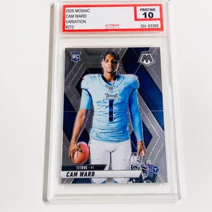Puede incluir: Una tarjeta de f&uacute;tbol de Cam Ward del set 2025 Mosaic, calificada como Pristine 10. La tarjeta presenta a Cam Ward con un uniforme de los Titans azul claro, sosteniendo un bal&oacute;n de f&uacute;tbol. La tarjeta est&aacute; dentro de un protector transparente con el texto "2025 MOSAIC CAM WARD VARIATION #272".