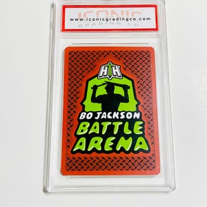 Peut inclure: Une carte &agrave; collectionner Bo Jackson Battle Arena dans un &eacute;tui de protection transparent. La carte pr&eacute;sente une silhouette d'une personne dans un design d'ar&egrave;ne vert et noir. Le texte "BO JACKSON BATTLE ARENA" est en vert et blanc. Le haut de l'&eacute;tui porte le texte "www.iconicgradingco.com".