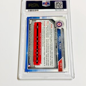 Op de afbeelding: Een honkbalkaart in een doorzichtige plastic hoes. De kaart toont Israel Pineda van de Washington Nationals. De kaart heeft een blauwe rand en bevat statistieken en biografische informatie.
