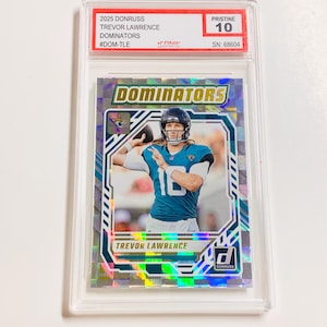 Op de afbeelding: Een 2025 Donruss Trevor Lawrence Dominators verzamelkaart, beoordeeld als Pristine 10, in een beschermende houder. De kaart toont Trevor Lawrence in een teal en zwart uniform. Het woord "Dominators" staat in grote, vette letters.