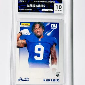 Könnte beinhalten: Eine bewertete Sammelkarte mit Malik Nabers in einem blauen Football-Trikot mit der Nummer 9. Die Karte stammt aus der Serie 2024 Panini Instant Studio Rookies und ist mit 10 GEM MT bewertet. Die Karte ist in einem transparenten Schutzhalter eingeschlossen.