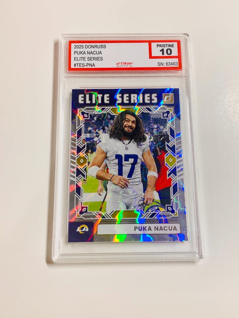 May include: A Puka Nacua Elite Series trading card from the 2025 Donruss set, graded Pristine 10. The card features a player in a white and blue uniform with the number 17. The card is encased in a clear protective holder.
