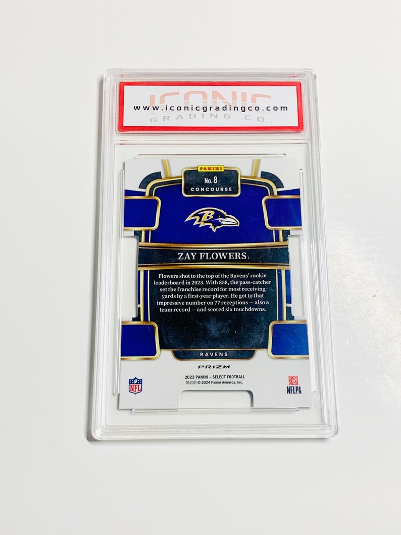 May include: A Zay Flowers football card from the 2023 Panini Select Football series. The card is graded by Iconic Grading Co. and features the Ravens' logo and player information. The card is encased in a protective holder.